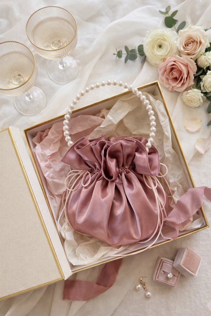 Pearl-handle pouch styled in a gift box with roses and champagne